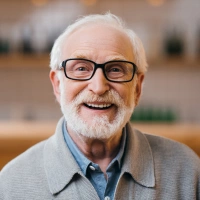 Older male patient smiling after dental implant treatment