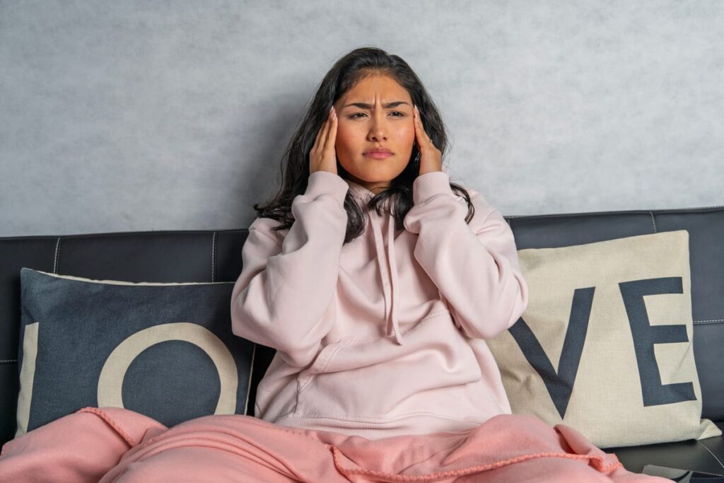 Woman holding her head experiencing jaw pain and headache symptoms.
